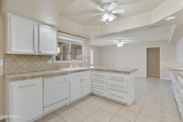 kitchen with kitchen peninsula, backsplash, sink, dishwasher, and white cabinetry