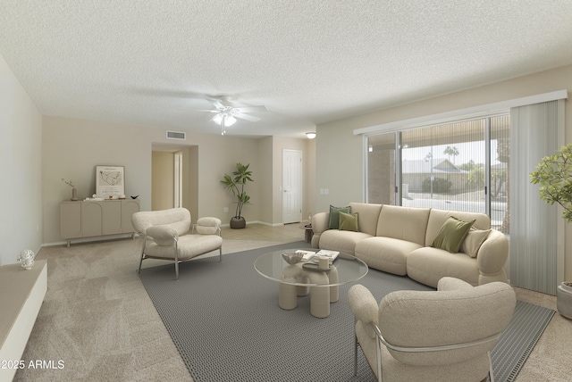 living room featuring ceiling fan, a textured ceiling, and light carpet