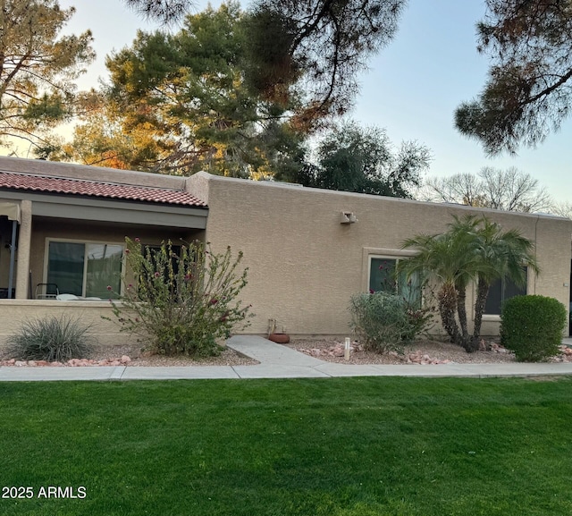 property exterior at dusk featuring a lawn