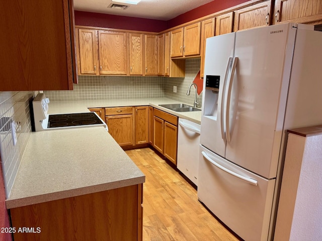 kitchen featuring decorative backsplash, white appliances, sink, and light hardwood / wood-style flooring