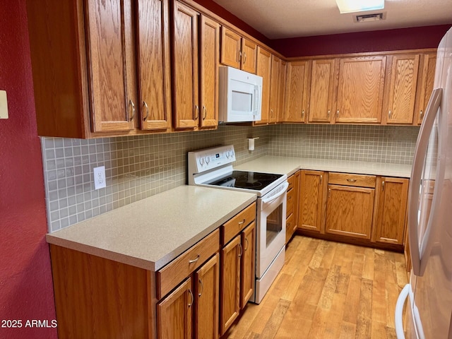 kitchen featuring backsplash, white appliances, and light hardwood / wood-style flooring