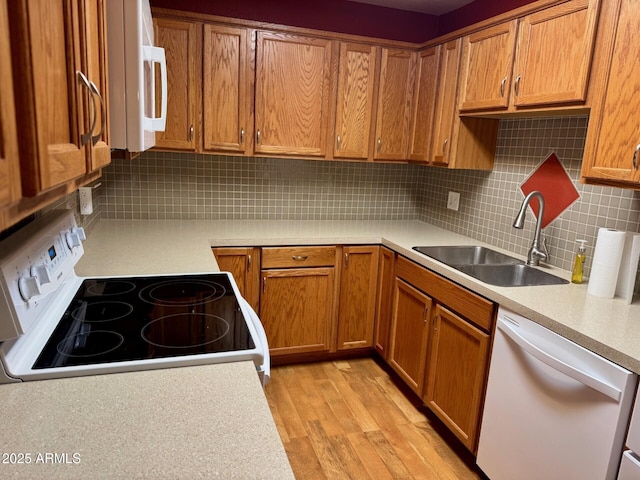 kitchen featuring tasteful backsplash, white appliances, sink, and light wood-type flooring