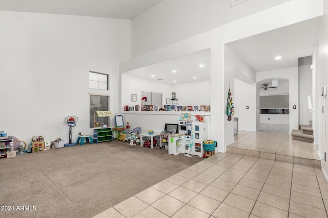 living room featuring light carpet, a towering ceiling, and ceiling fan