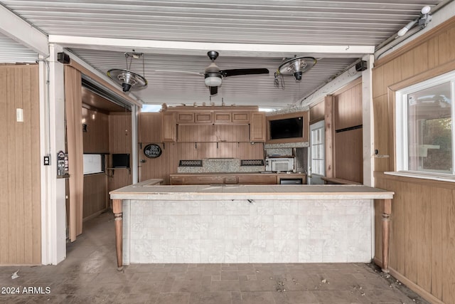 kitchen featuring ceiling fan, wood walls, and kitchen peninsula