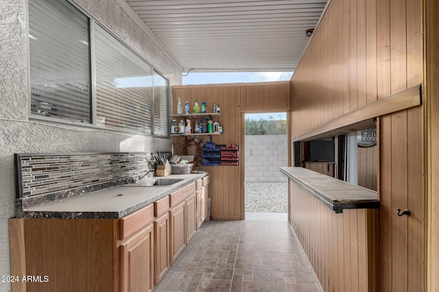 bar featuring sink and wood walls