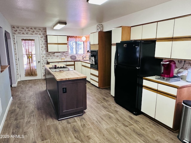 kitchen with sink, a center island, black appliances, white cabinets, and light wood-type flooring