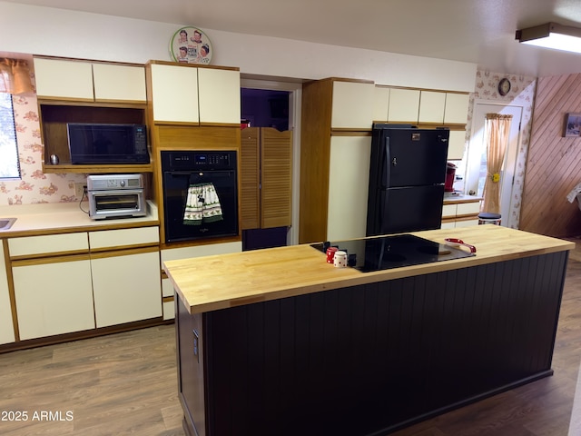 kitchen with wood-type flooring, white cabinets, and black appliances