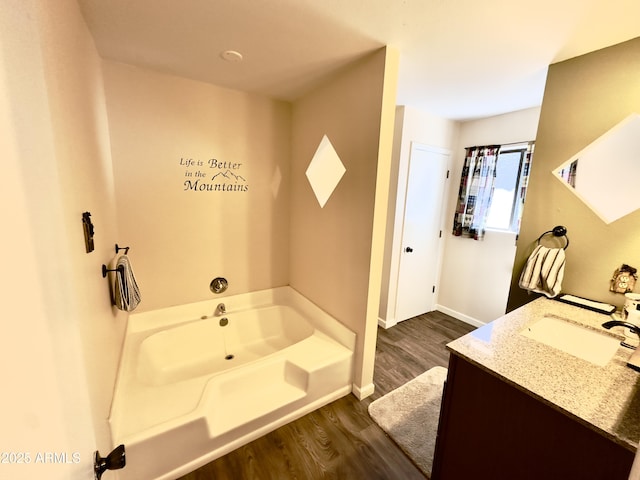 bathroom with hardwood / wood-style flooring, a tub to relax in, and vanity