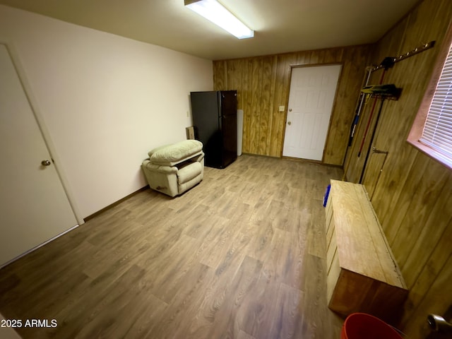 unfurnished room featuring wooden walls and light hardwood / wood-style floors