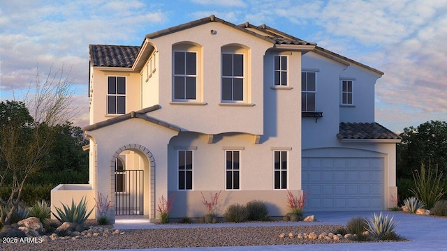 mediterranean / spanish-style home with a garage, driveway, a tiled roof, and stucco siding