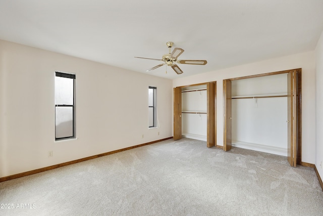 unfurnished bedroom featuring a ceiling fan, baseboards, two closets, and light colored carpet