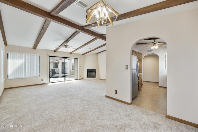 spare room with visible vents, arched walkways, light colored carpet, lofted ceiling with beams, and a fireplace