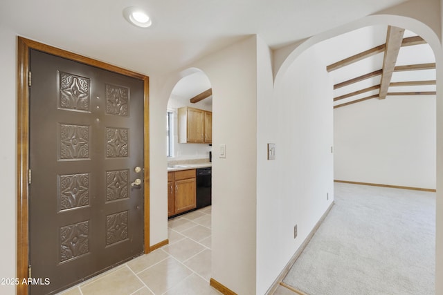 foyer with light colored carpet, vaulted ceiling with beams, baseboards, and light tile patterned floors