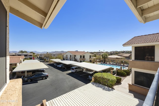 uncovered parking lot featuring a residential view, an outdoor pool, and a mountain view