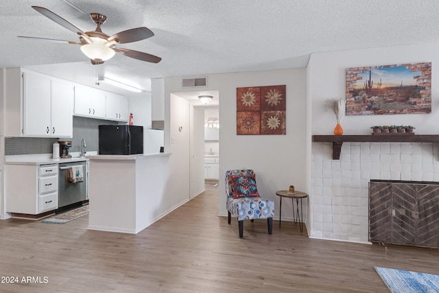 kitchen featuring black refrigerator, white cabinetry, light hardwood / wood-style floors, stainless steel dishwasher, and kitchen peninsula