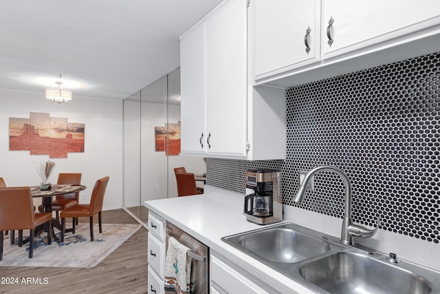 kitchen with a sink, light wood-type flooring, white cabinetry, light countertops, and stainless steel dishwasher