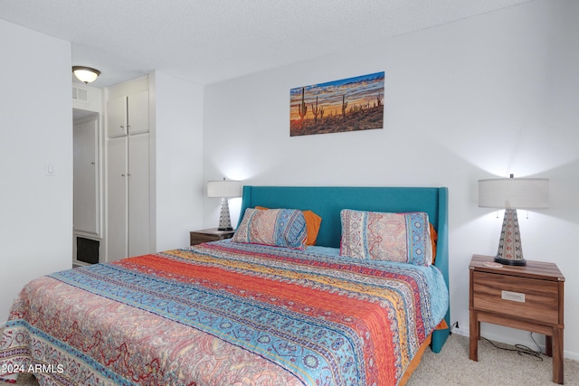carpeted bedroom featuring a textured ceiling, visible vents, and baseboards