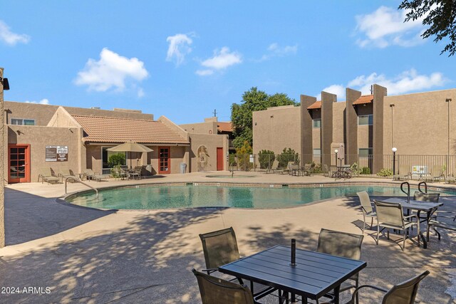 community pool with fence, outdoor dining space, and a patio area