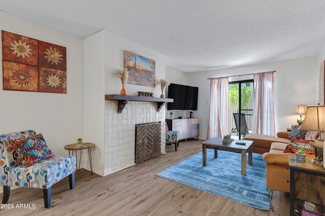 living room featuring a fireplace, light hardwood / wood-style flooring, and a textured ceiling