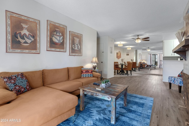 living room featuring hardwood / wood-style flooring, ceiling fan, and a textured ceiling