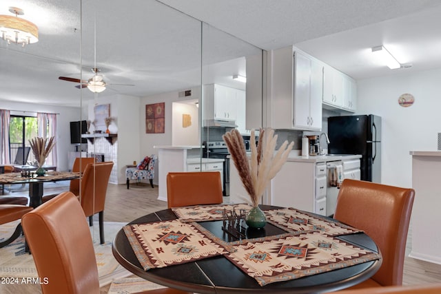 dining space featuring a textured ceiling, light wood-type flooring, a ceiling fan, and baseboards