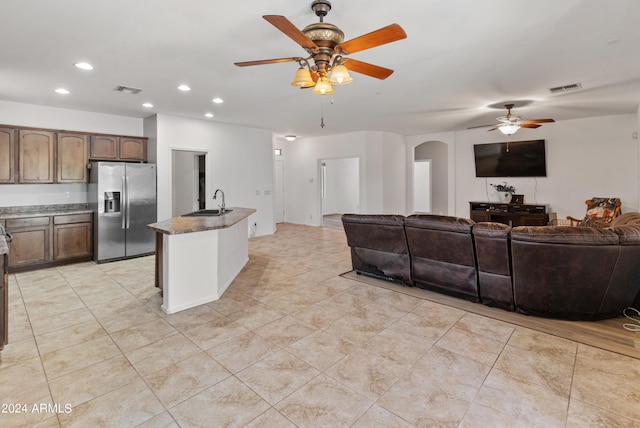 kitchen with ceiling fan, a kitchen island with sink, light tile patterned flooring, and stainless steel refrigerator with ice dispenser