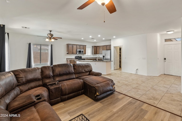 living room featuring ceiling fan, sink, and light hardwood / wood-style flooring