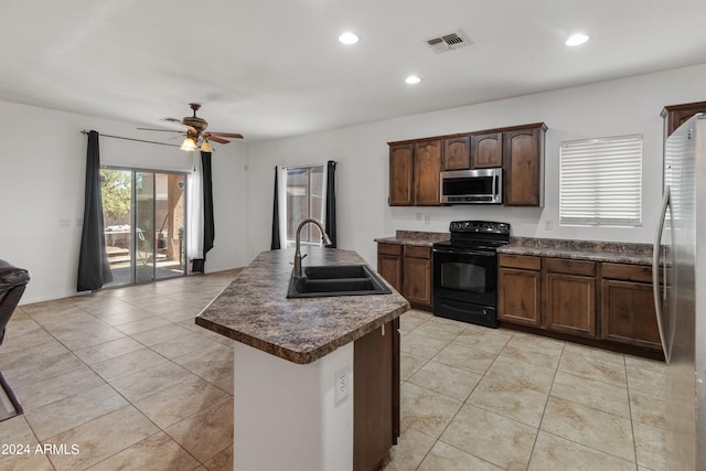 kitchen with sink, light tile patterned floors, appliances with stainless steel finishes, a kitchen island with sink, and ceiling fan