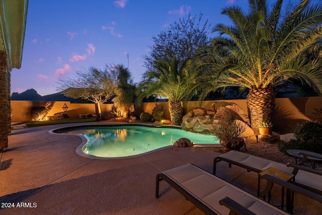 pool at dusk featuring a patio