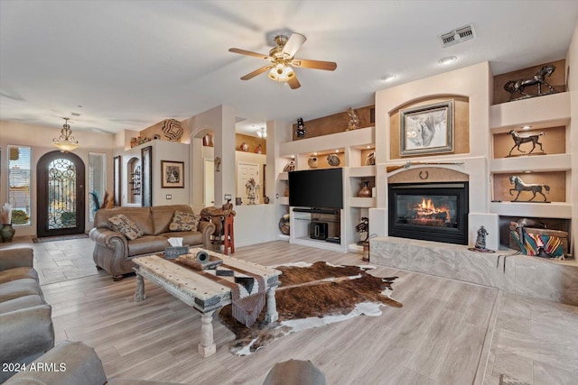 living room featuring light hardwood / wood-style flooring, built in features, and ceiling fan