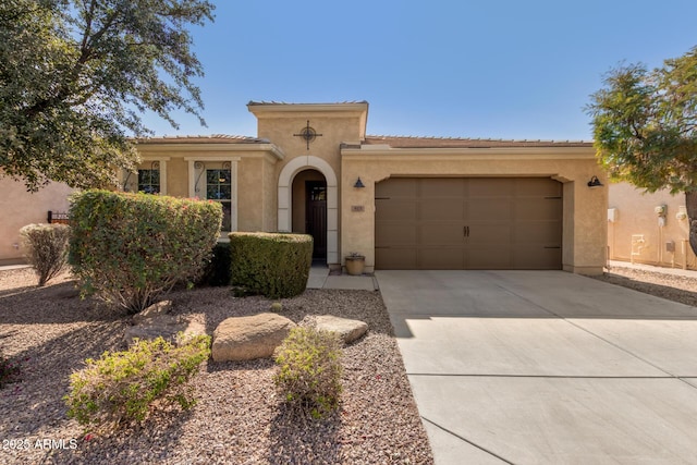 mediterranean / spanish home with a garage, concrete driveway, a tiled roof, and stucco siding