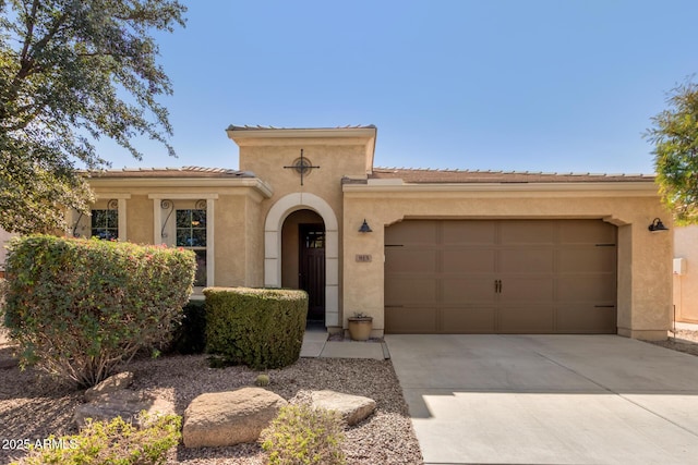 mediterranean / spanish house featuring a garage, driveway, a tile roof, and stucco siding