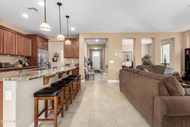 815 E Laddoos Ave, San Tan Valley, AZ 85140 - kitchen featuring open floor plan, light stone countertops, stainless steel refrigerator with ice dispenser, a kitchen bar, and pendant lighting