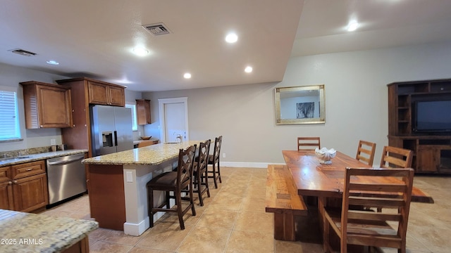 5539 E Dragoon Ave, Mesa, AZ 85206 - kitchen with appliances with stainless steel finishes, a kitchen island with sink, a kitchen bar, recessed lighting, and light tile patterned floors