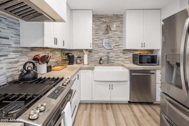 7707 E Earll Dr, Scottsdale, AZ 85251 - kitchen featuring appliances with stainless steel finishes, wall chimney range hood, a sink, backsplash, and light countertops