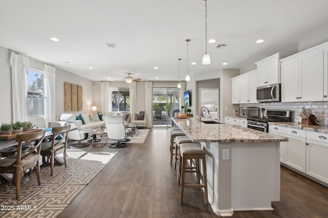 kitchen with white cabinetry, stainless steel appliances, a large island, and hanging light fixtures