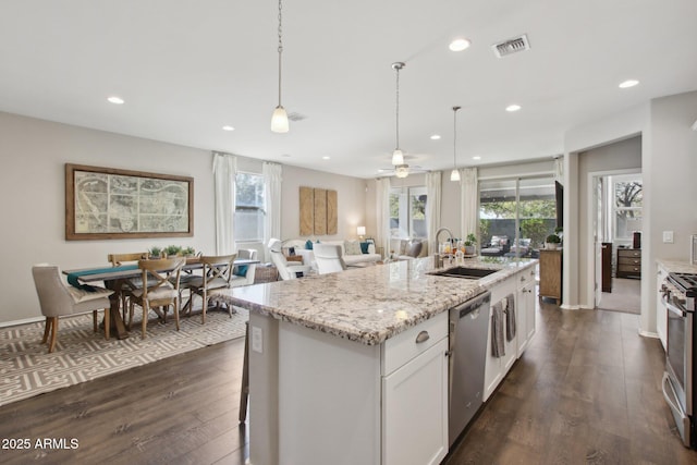 kitchen with sink, white cabinetry, decorative light fixtures, an island with sink, and stainless steel appliances