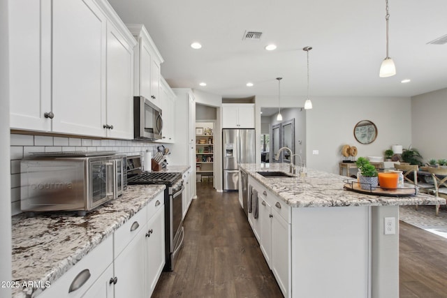 kitchen with white cabinetry, appliances with stainless steel finishes, a kitchen island with sink, and sink