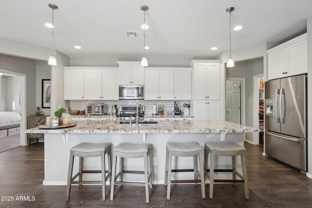 kitchen featuring a kitchen island with sink, hanging light fixtures, and stainless steel appliances