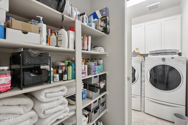 clothes washing area featuring cabinets, washer and dryer, and light tile patterned floors