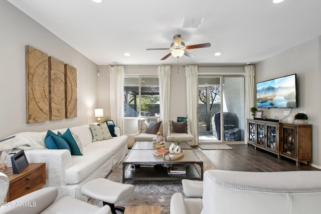 living room featuring dark wood-type flooring and ceiling fan