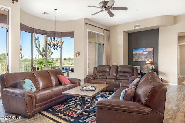 living room featuring wood-type flooring and ceiling fan with notable chandelier