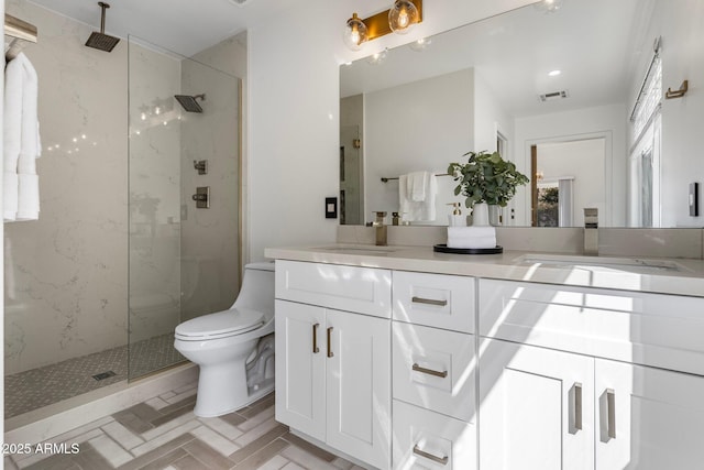 bathroom featuring double vanity, toilet, a marble finish shower, and a sink