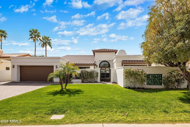 mediterranean / spanish house featuring stucco siding, decorative driveway, a front yard, an attached garage, and a tiled roof