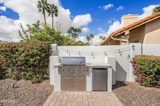 view of patio featuring exterior kitchen, fence, and a grill