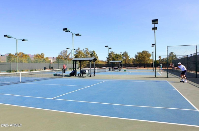 view of tennis court with community basketball court and fence