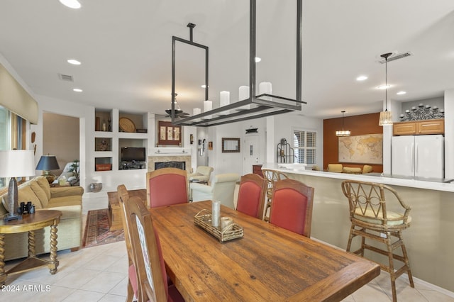 dining room featuring built in shelves, a notable chandelier, and light tile patterned floors