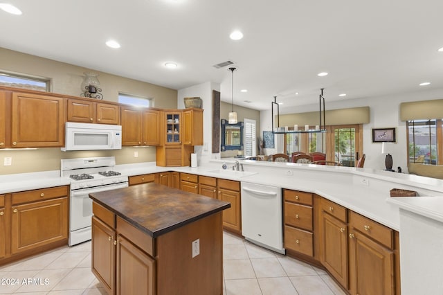 kitchen featuring white appliances, light tile patterned floors, hanging light fixtures, sink, and kitchen peninsula