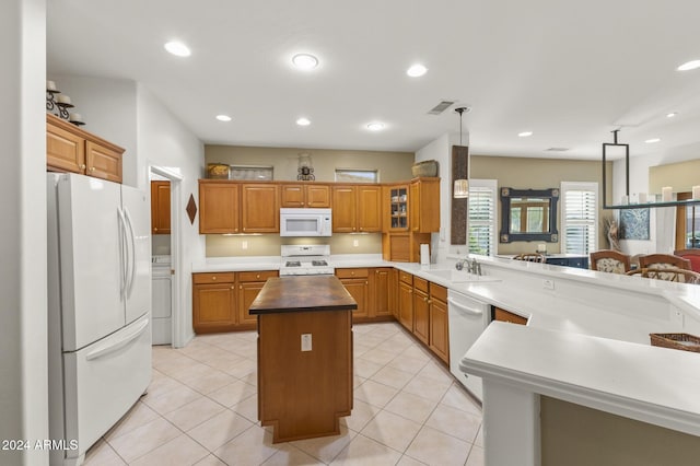 kitchen featuring butcher block counters, kitchen peninsula, pendant lighting, white appliances, and a center island