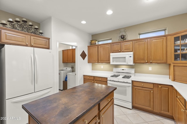 kitchen with white appliances, independent washer and dryer, and light tile patterned flooring